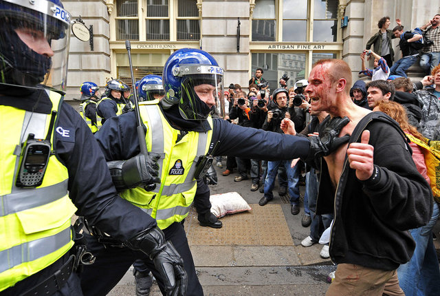 Полицейский сдерживает возбужденного окровавленного протестующего около Государственного банка Англии, в Лондоне, 1 апреля 2009. (CARL DE SOUZA/AFP/Getty Images) 