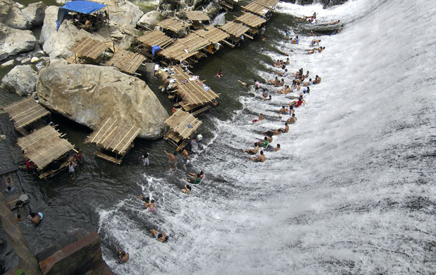 2 апреля. Montalban, Филиппины. Местные жители, спасаясь от жары, купаются в потоках воды, переливающихся через дамбу в области Rizal. Photograph: Jes Aznar/AFP/Getty Images