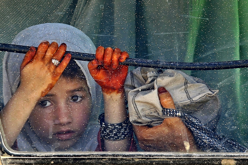 Афганская девочка смотрит из окна автобуса на канадских солдат. Кандагар.