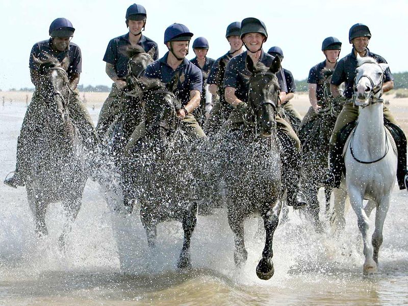 31) Солдаты полка домашней кавалерии упражняются на лошадях на пляже Холкэм, Великобритания, во время трехнедельной летней тренировки и в перерыве между церемониальными обязанностями. (Dominic Lipinski, Press Association)