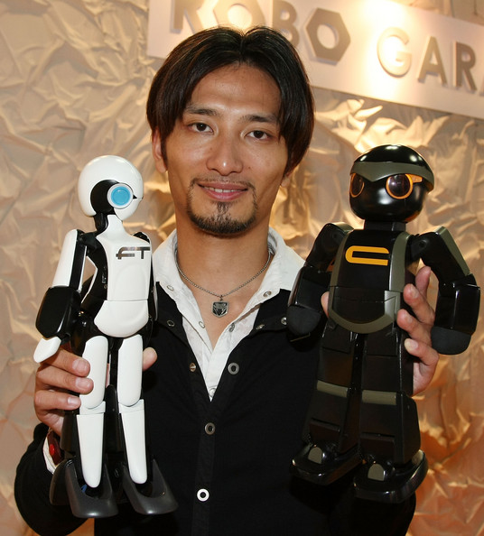 Разработчик роботов Tomotaka Takahashi держит в руках две модели андроидов Chroino и FT, созданные им в сотрудничестве с компанией Robo Garage.